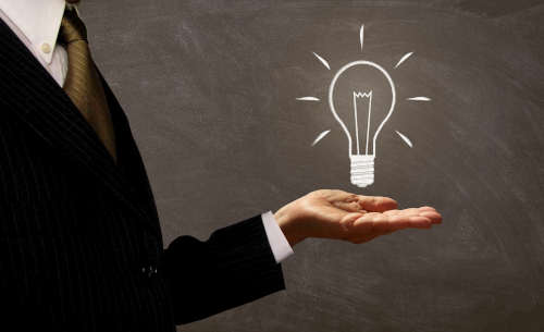 businessman-holding-light-bulb-on-chalkboard